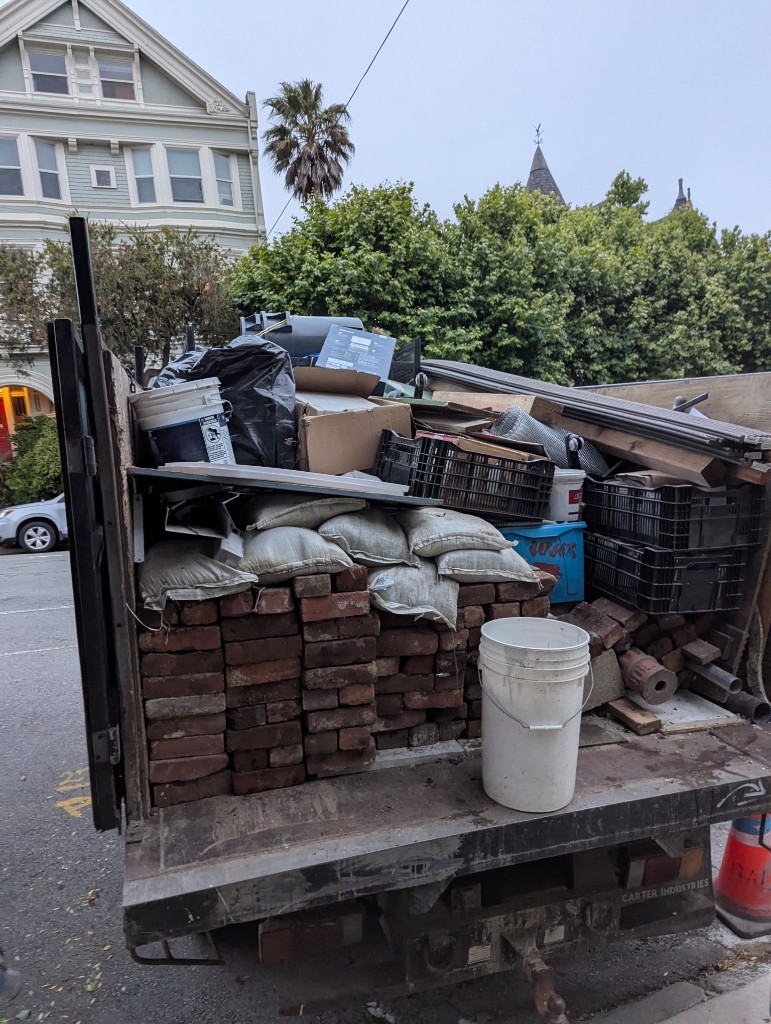 Loaded hauling truck with bricks, lumber, and debris on a residential street